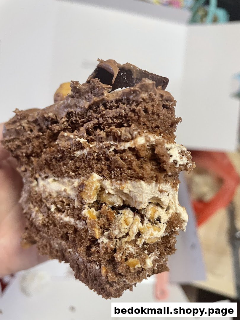 Close-up of a chocolate cake slice with cream and nuts.