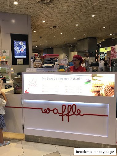 Shop counter with staff, waffle sign, and menu display.