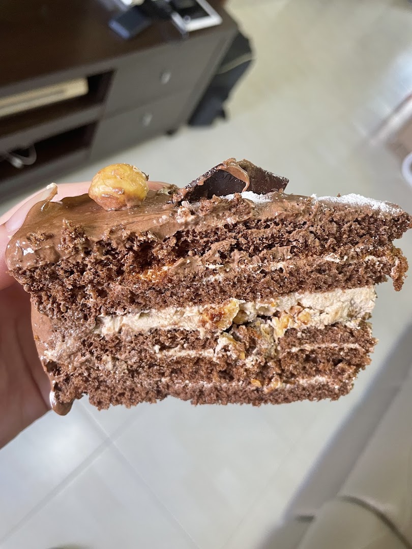 Close-up of a layered chocolate cake slice with cream and nuts.