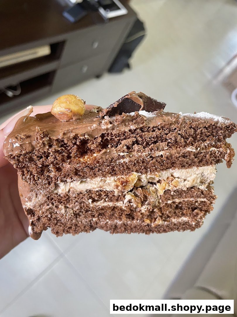 Close-up of a layered chocolate cake slice with cream and nuts.