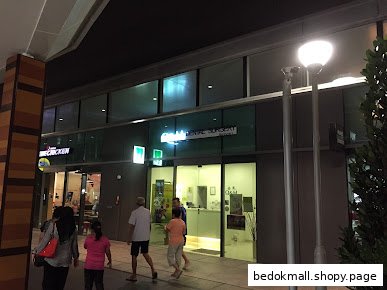 Exterior view of Q&M Dental Surgery with people walking by at night.