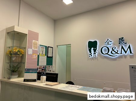 Interior view of a dental clinic reception desk with Q&M logo.