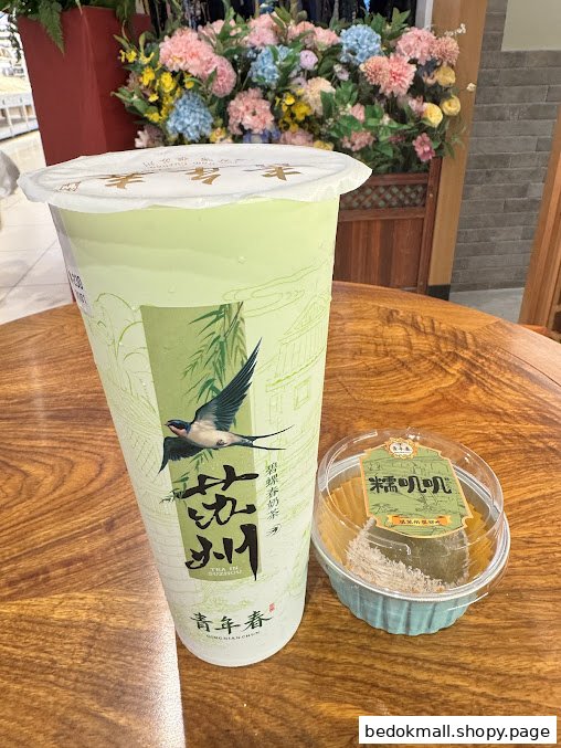 A large green drink and a small dessert on a wooden table.