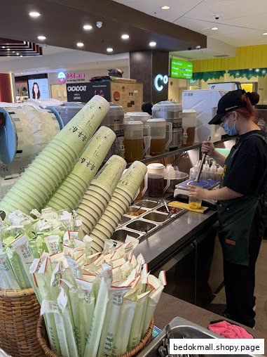 Staff member preparing drinks behind a counter with cups and straws.