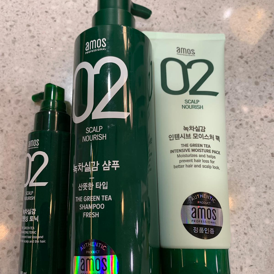 Close-up of three green Amos Professional hair care products.