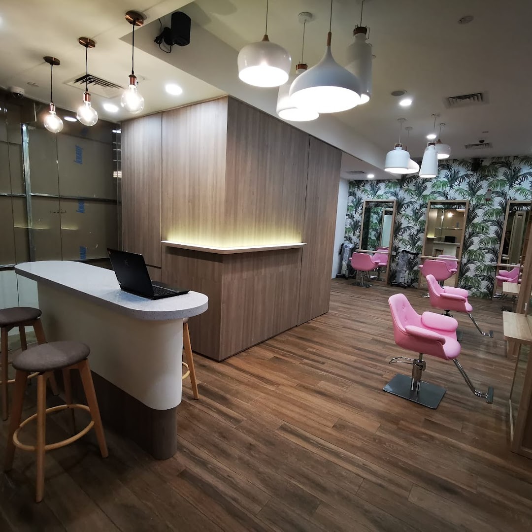 Interior view of a hair salon with a reception desk and pink chairs.
