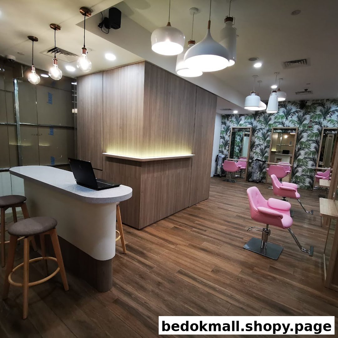 Interior view of a hair salon with a reception desk and pink chairs.