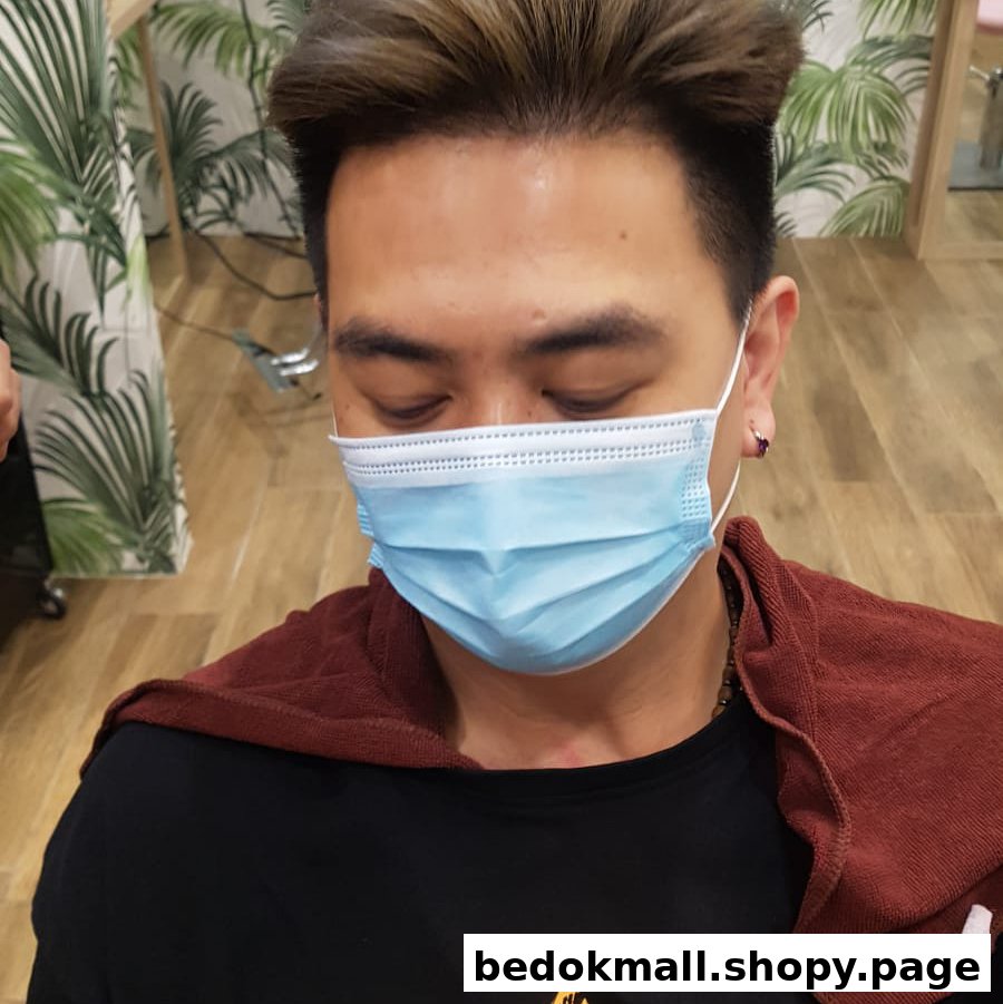 A person wearing a face mask and a red cape in a hair salon.