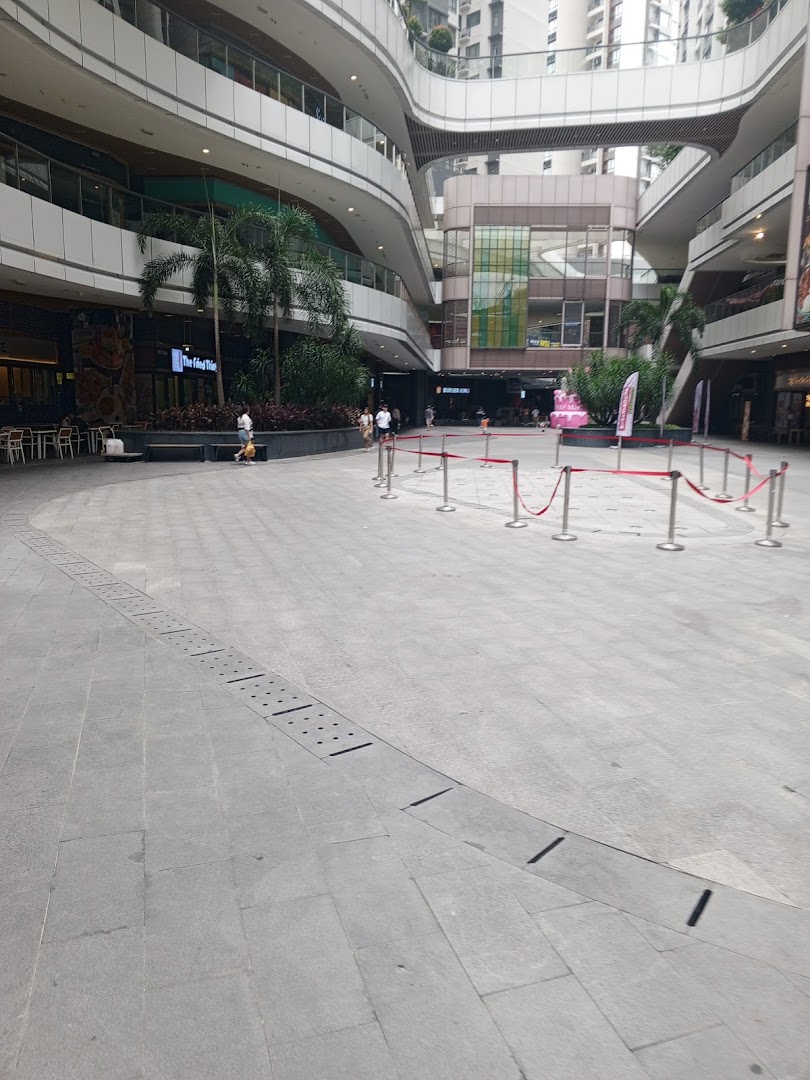 A large, multi-level shopping mall plaza with various shops and people.