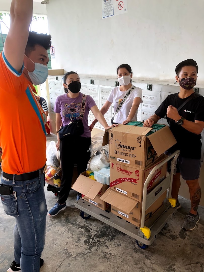 People in masks with a cart full of boxes near mailboxes.