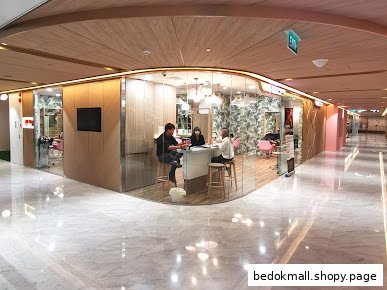 Hair salon with glass walls showing customers and staff inside a mall.