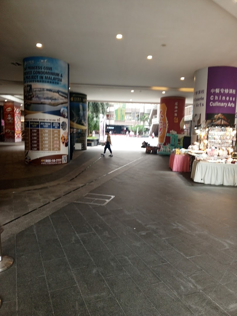 Covered walkway with pillars, a person, and market stalls.