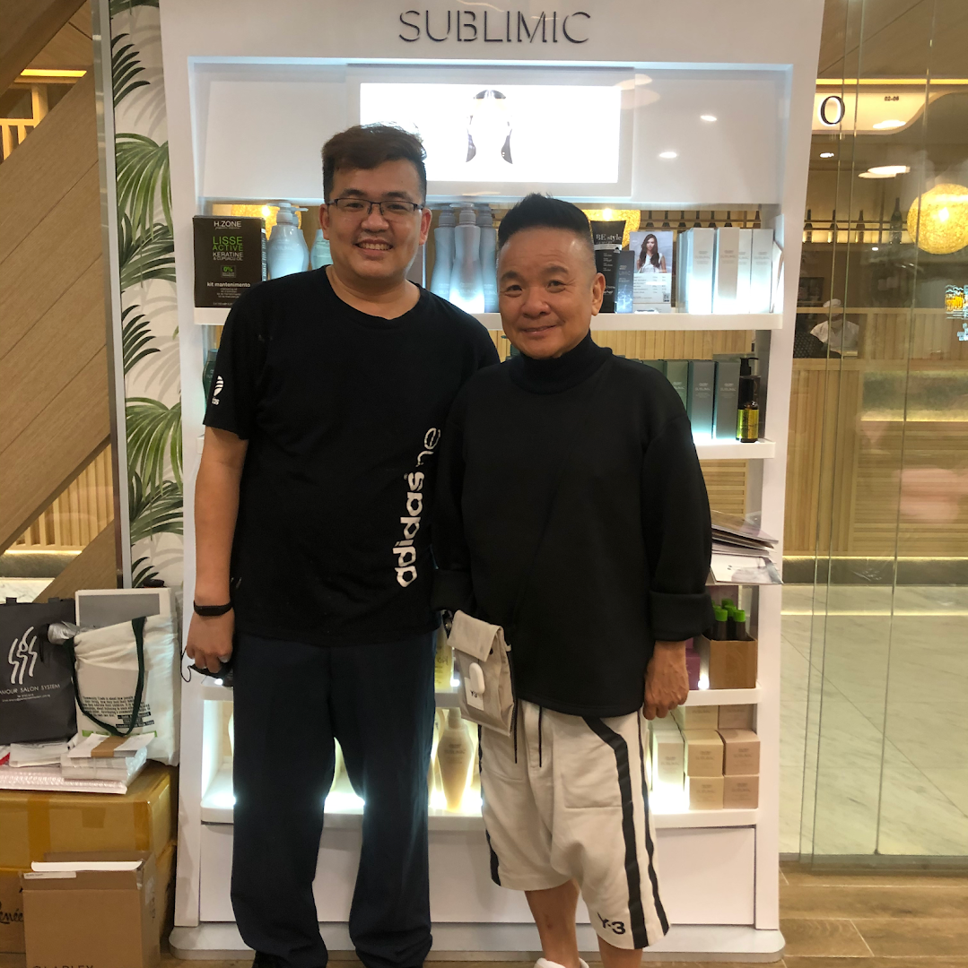 Two men standing in front of a hair product display shelf inside the salon.