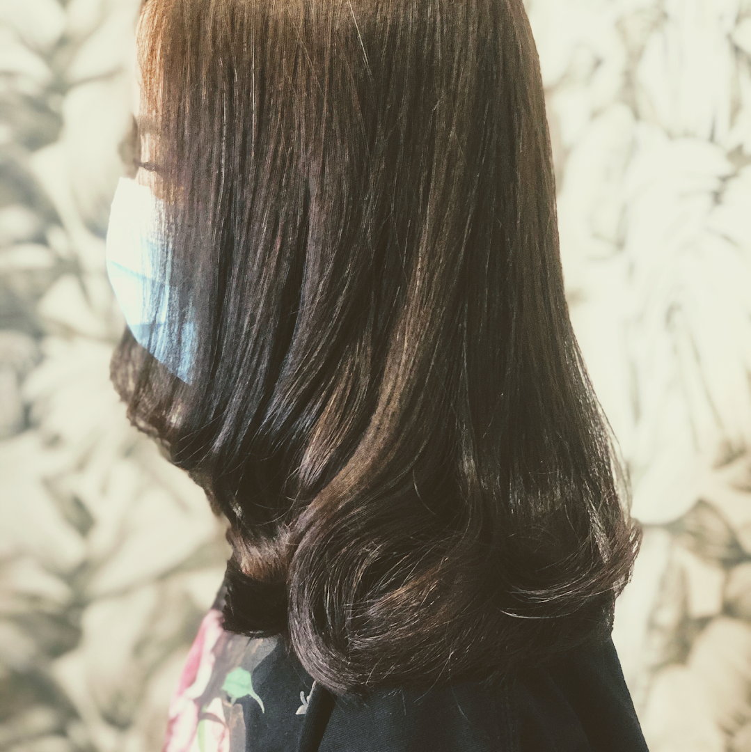 Side view of a person with styled dark hair and a face mask.