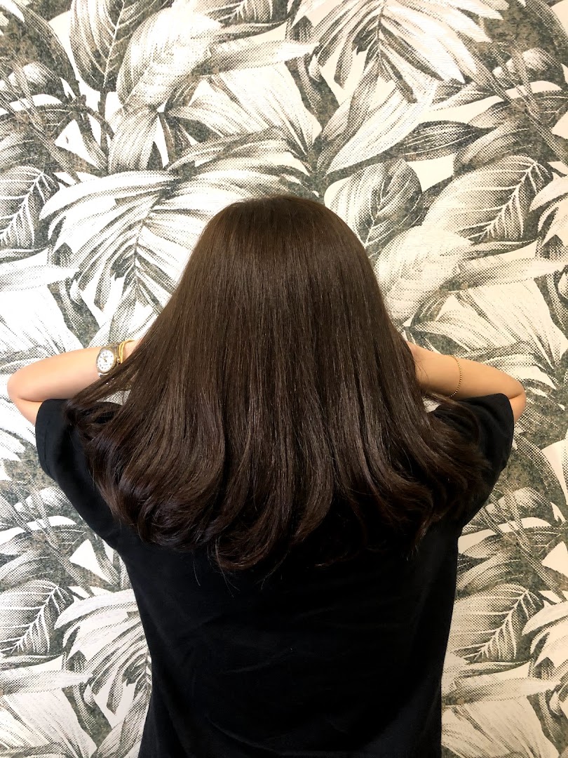 Back of person's head with long dark hair against a patterned wall.