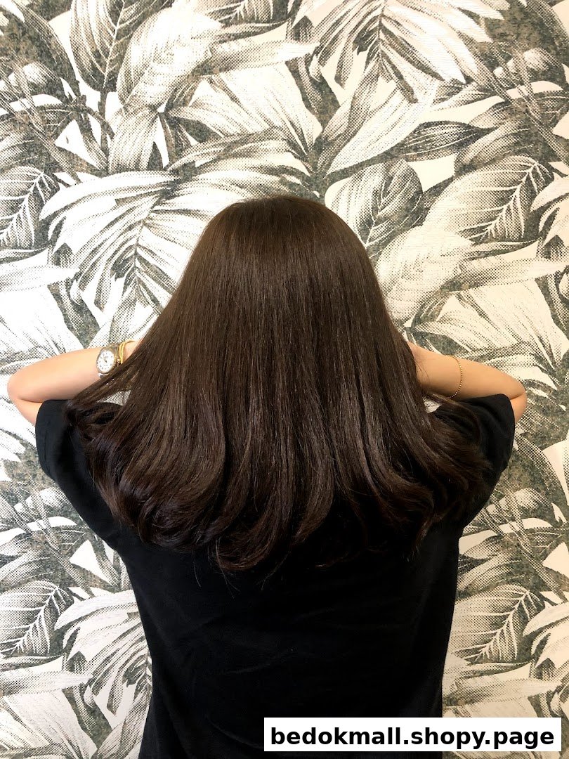 Back of person's head with long dark hair against a patterned wall.