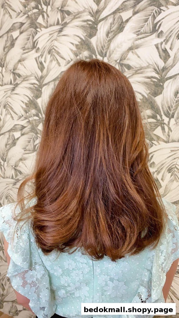 Back of a person with styled reddish-brown hair and a light blue top.