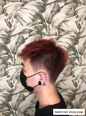 Person with red hair and fade haircut wearing a mask against a patterned wall.