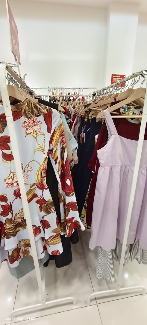 Racks of colorful clothes, including dresses, inside a retail shop.