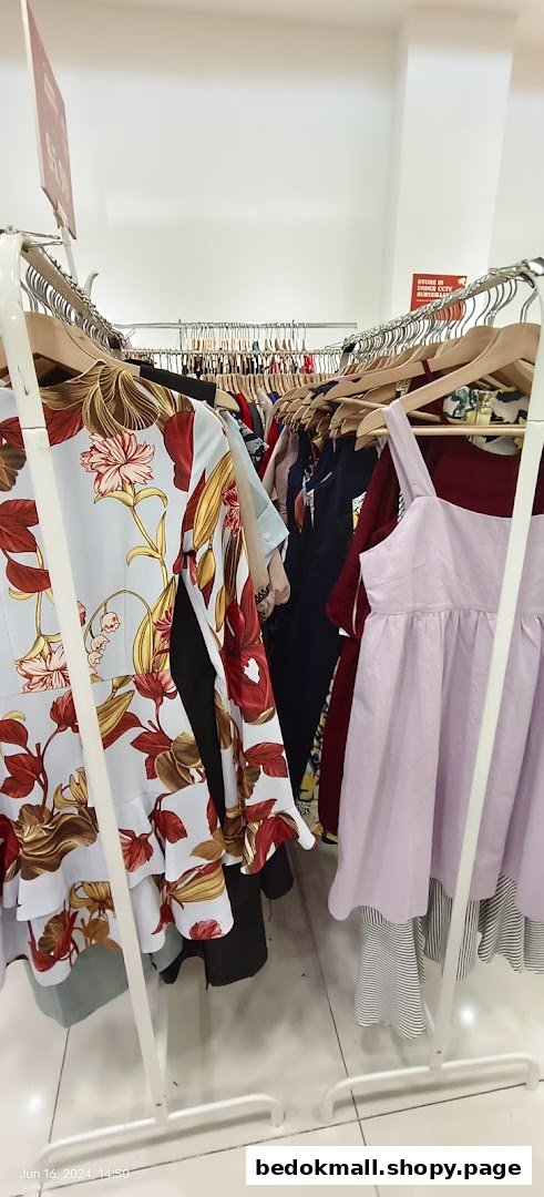 Racks of colorful clothes, including dresses, inside a retail shop.