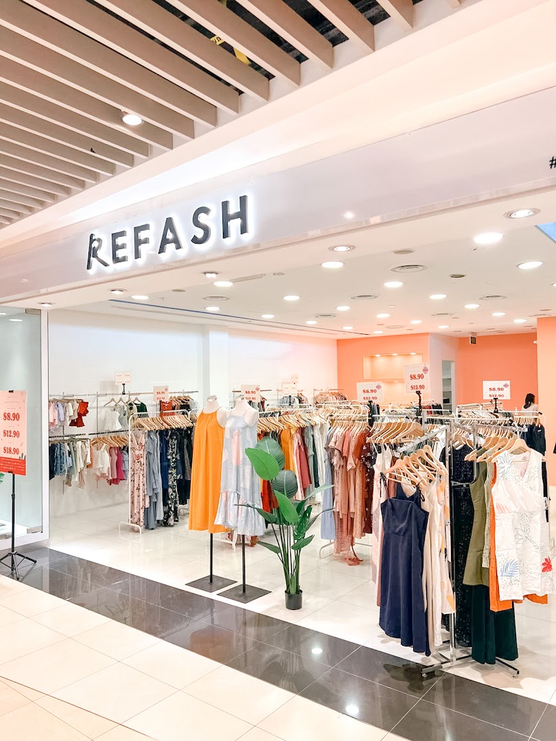 Front view of REFASH clothing store with racks of apparel and mannequins.