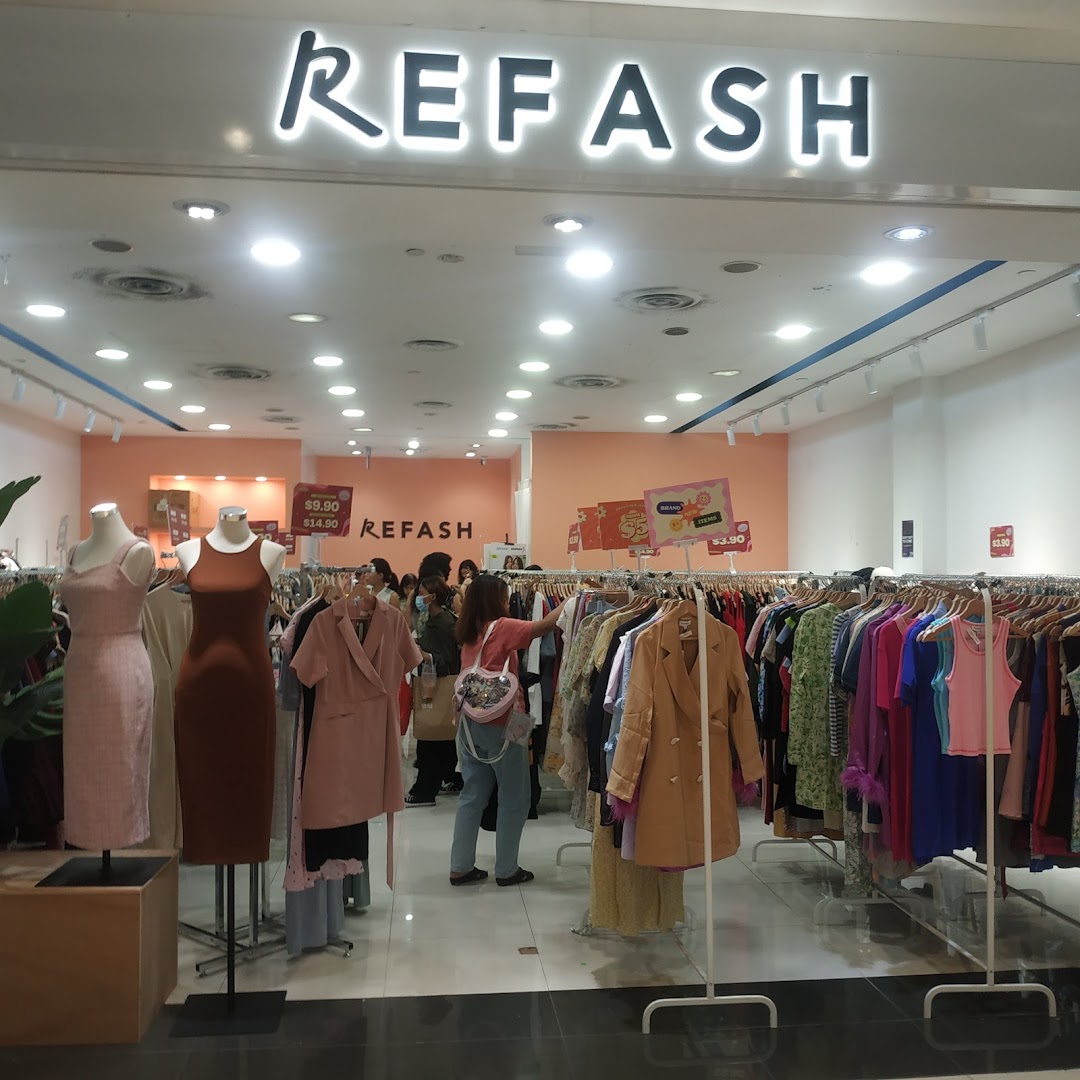 Entrance of a clothing shop with mannequins and racks of clothes.