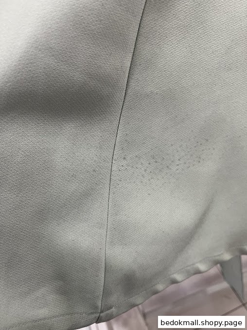 Close-up of light-colored fabric with a seam and dark spots.