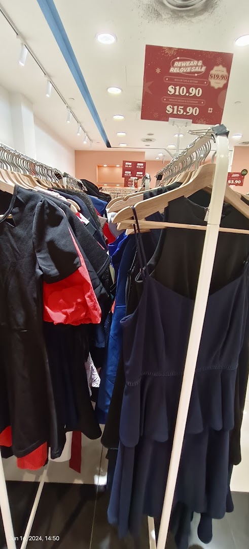 Clothing on racks inside a retail store with a sale sign visible.