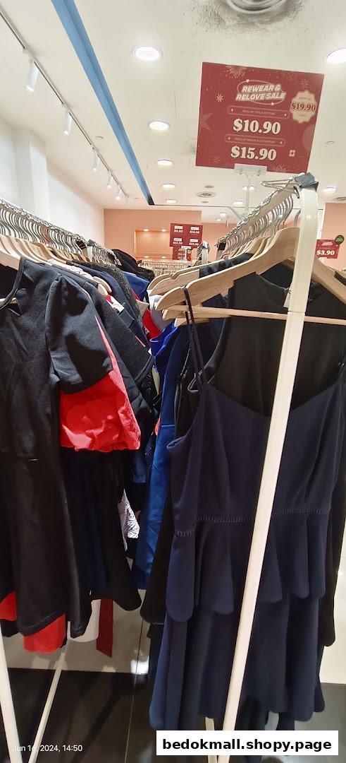 Clothing on racks inside a retail store with a sale sign visible.