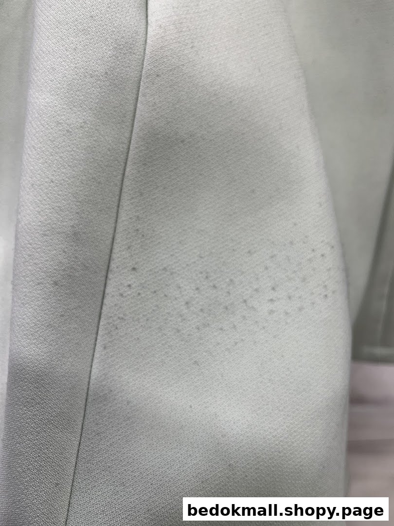 Close-up of light-colored fabric with small dark spots or stains.
