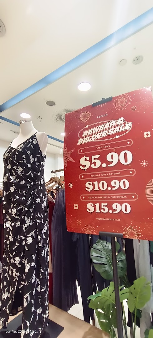 Mannequin and a sale sign with clothing prices inside a shop.