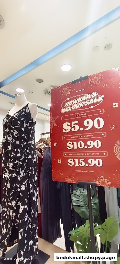Mannequin and a sale sign with clothing prices inside a shop.