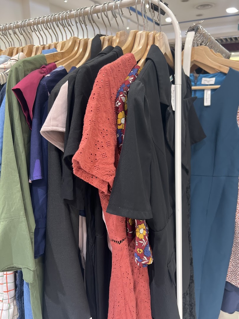 Various clothes hanging on a retail display rack inside a shop.