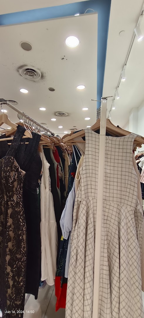 Clothes on hangers inside a retail store, with ceiling lights visible.