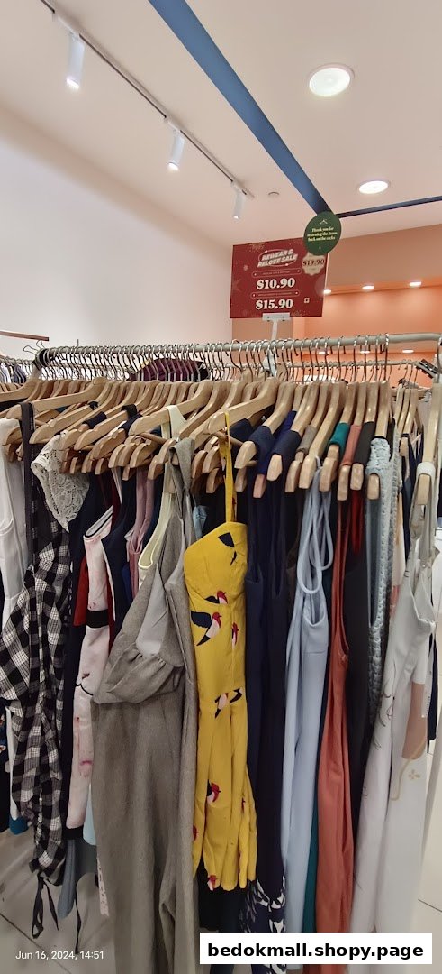 Clothing rack with various garments and a sale sign in a retail store.