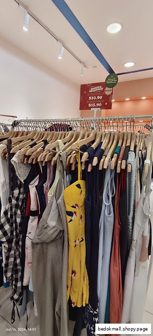 Clothing rack with various garments and a sale sign inside a shop.