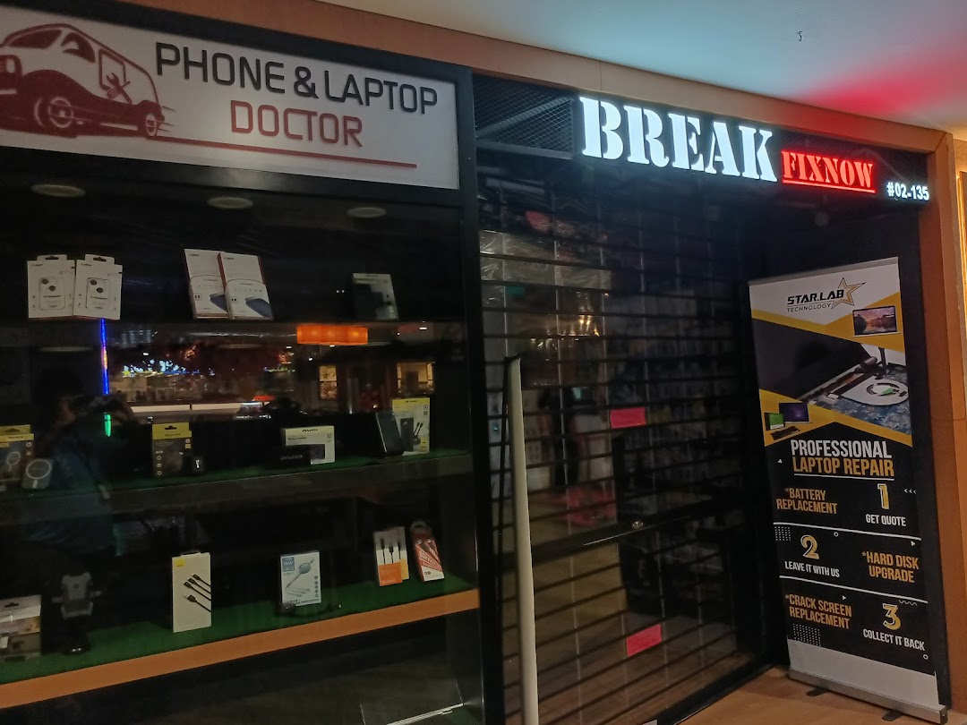 Shop front of a phone and laptop repair center with display and closed shutter.