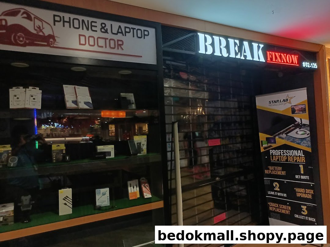 Shop front of a phone and laptop repair center with display and closed shutter.