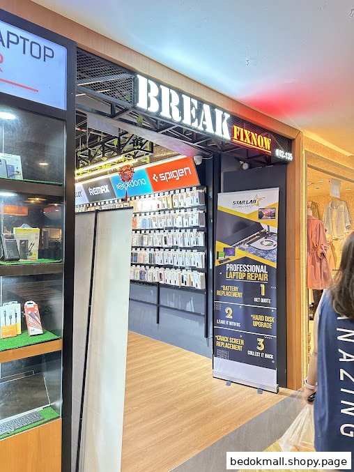 View of a phone and laptop repair shop entrance with product displays.