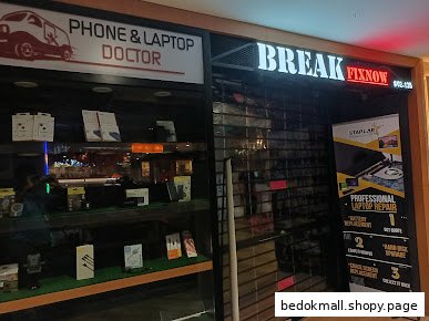 Exterior of a closed phone and laptop repair shop with display windows.