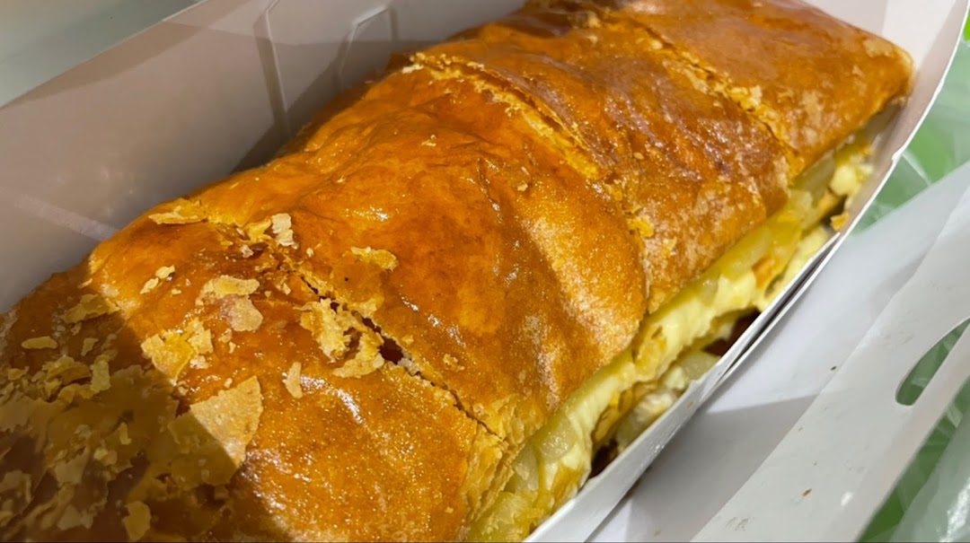 A golden-brown strudel with flaky crust in a white box.