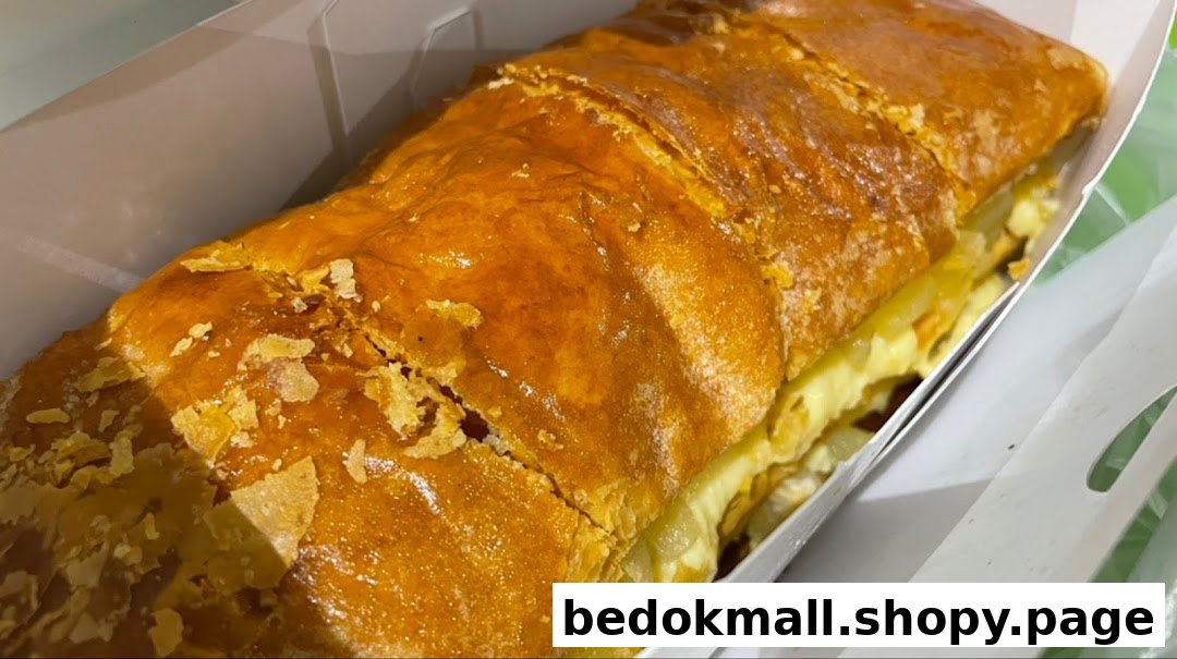 A golden-brown strudel with flaky crust in a white box.