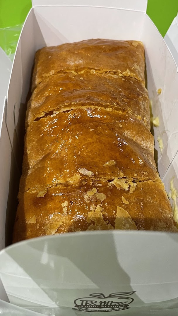 Close-up of a golden brown strudel in a white box.
