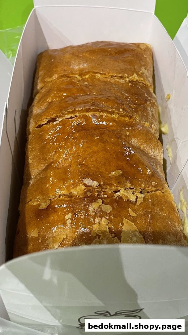 Close-up of a golden brown strudel in a white box.