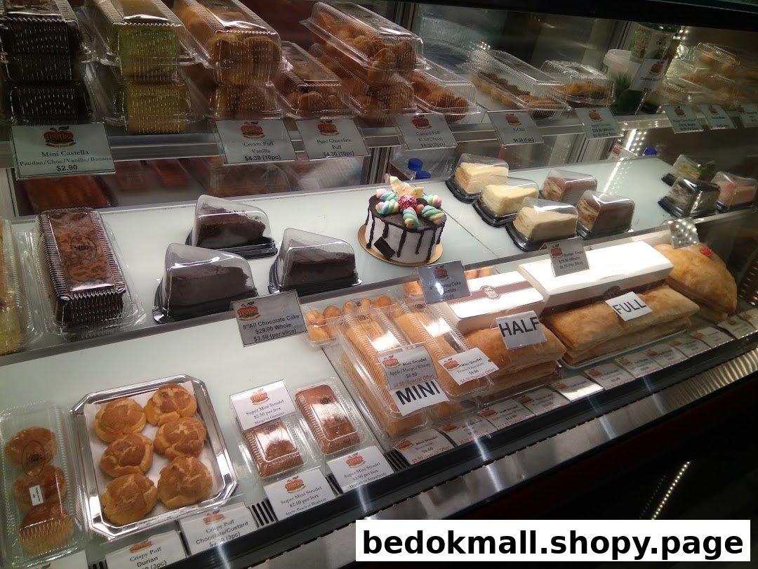A display case filled with various cakes, pastries, and strudels with price tags.