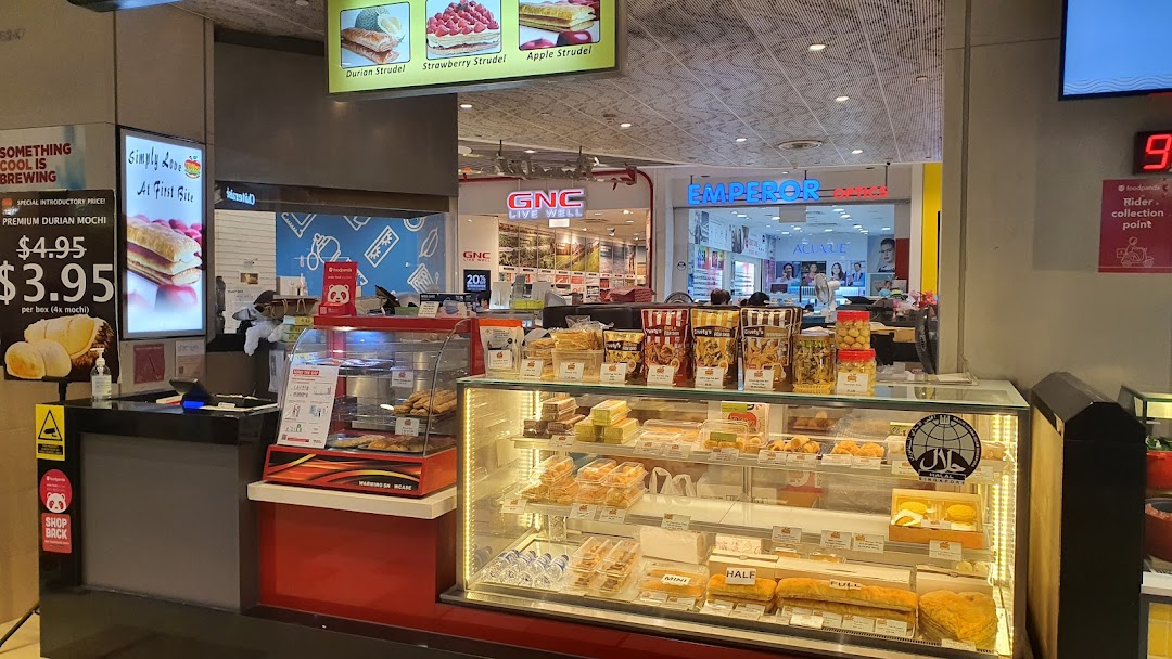 Food stall counter with display cases full of pastries and a price list.