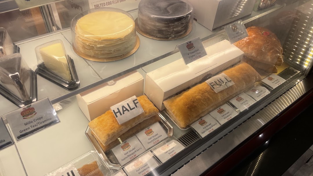 Display case filled with various cakes and strudels for sale.