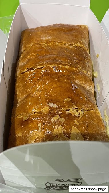 A golden-brown apple strudel in a white box.