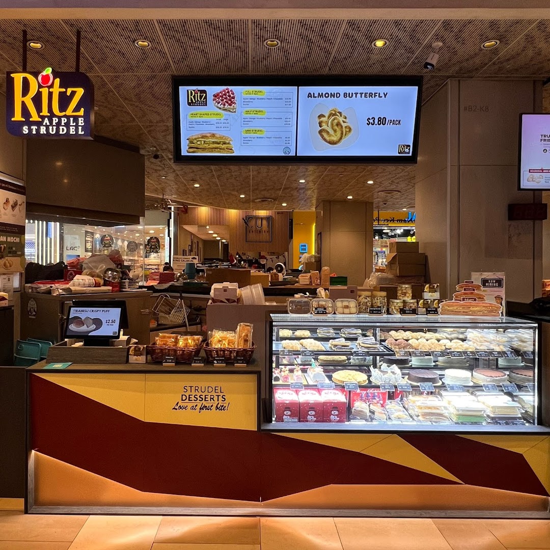 Interior view of a dessert shop counter with display case and menu board.