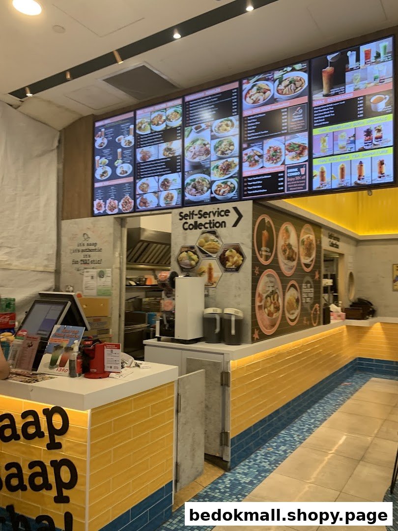 Interior view of a Thai food shop with large menu boards and a counter.